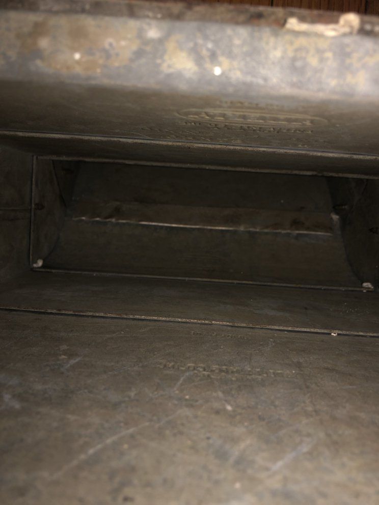 Inside view of a rectangular, metal air duct, with seams and some discoloration visible.