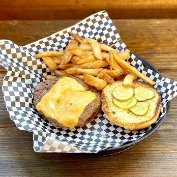 A hamburger and french fries in a basket on a wooden table.