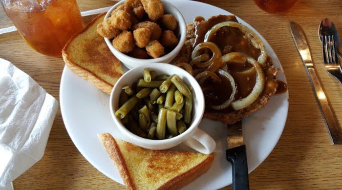 A white plate topped with a steak , green beans , fried chicken nuggets and toast.