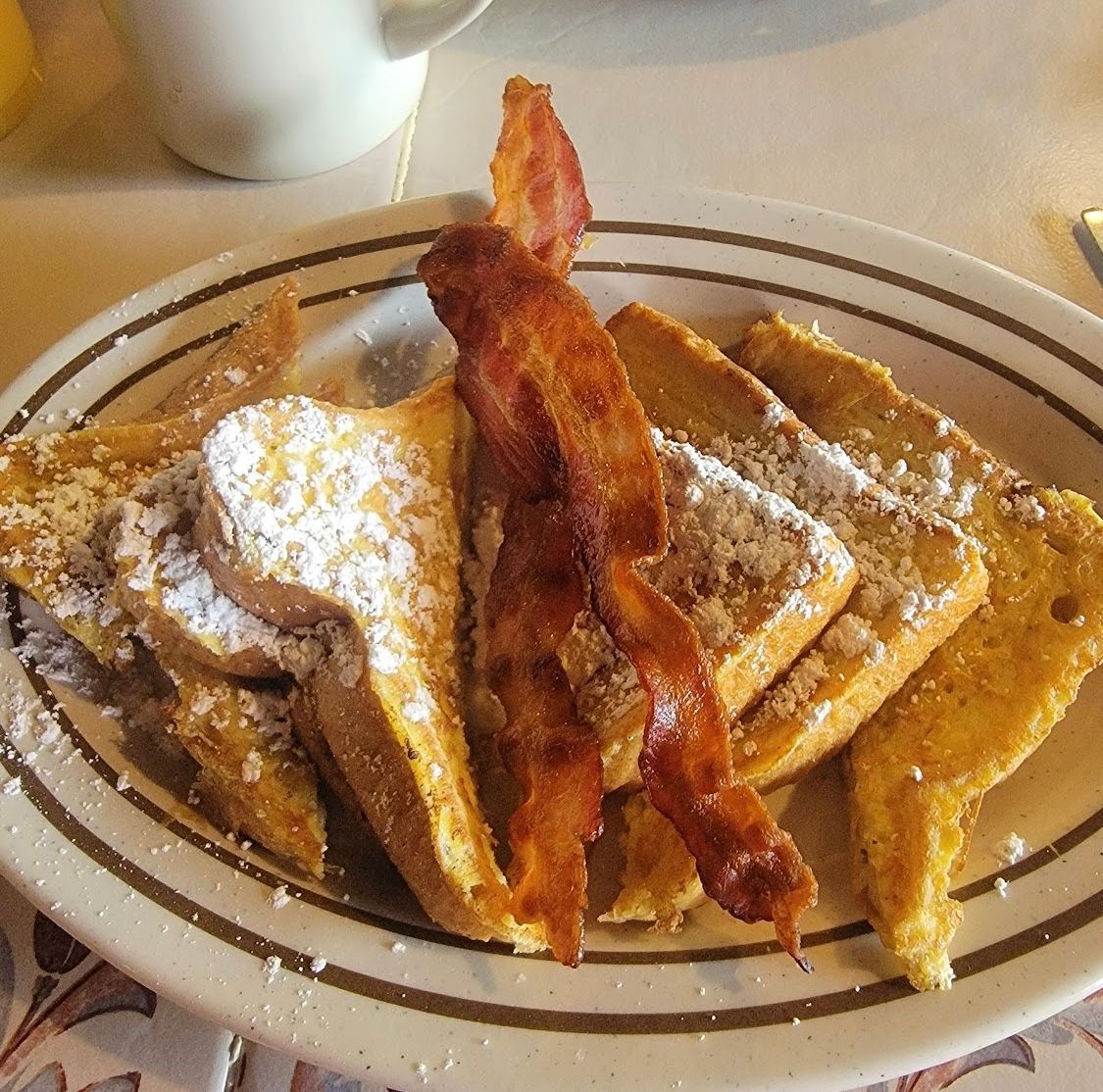 French toast with bacon and powdered sugar on a plate