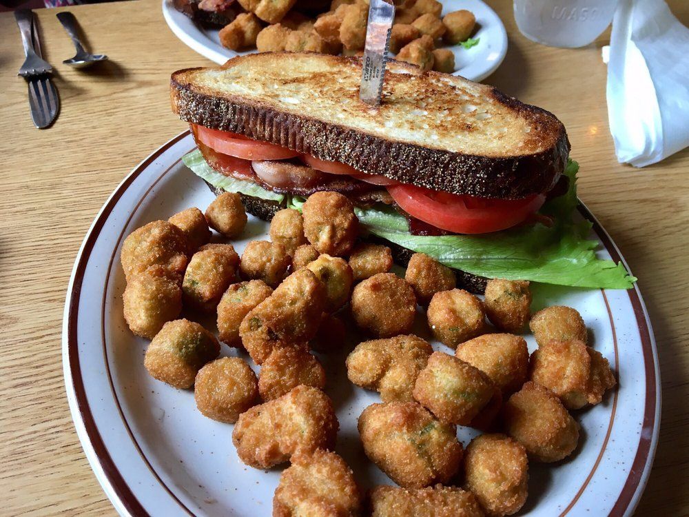 A plate of food with a sandwich and fried pickles on it