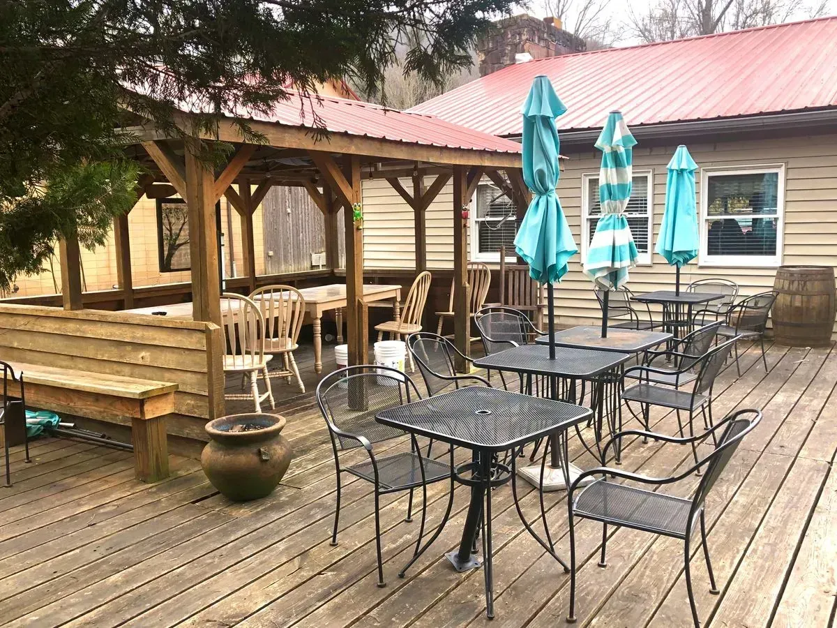 A wooden deck with tables and chairs and umbrellas in front of a building.