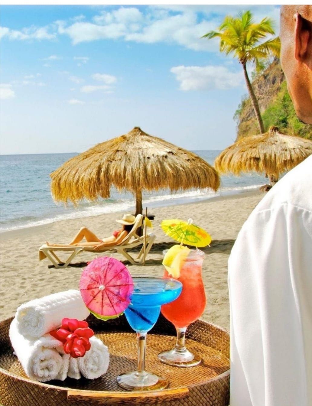 A man is holding a tray of drinks on the beach