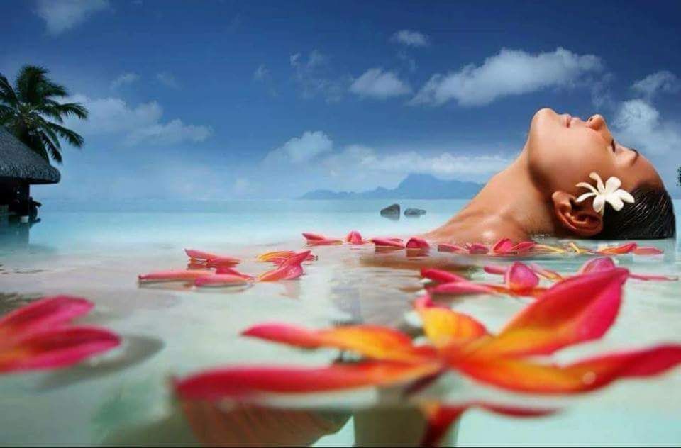 A woman is laying in the water with flowers in her hair