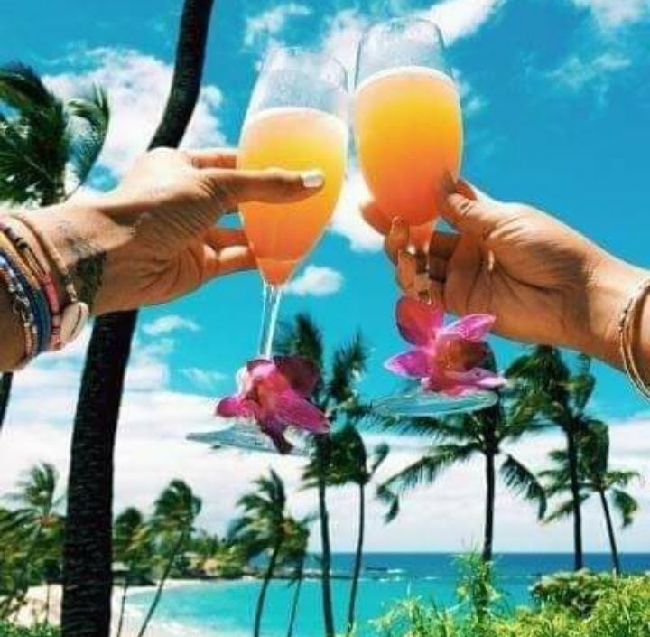 Two people are toasting with champagne glasses on the beach.