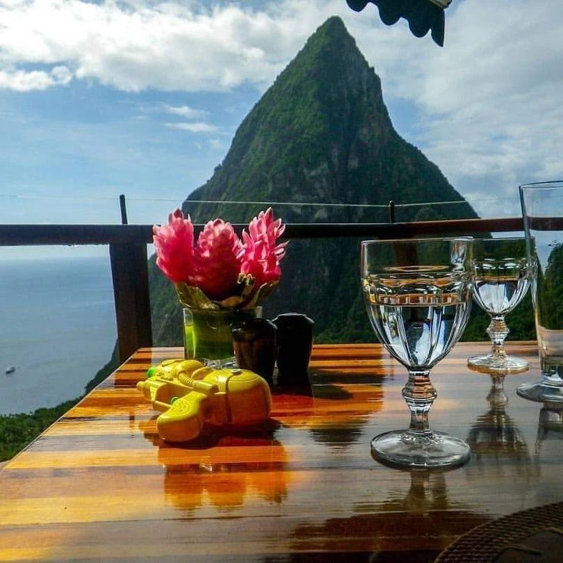 A table with a mountain in the background and a vase of flowers on it