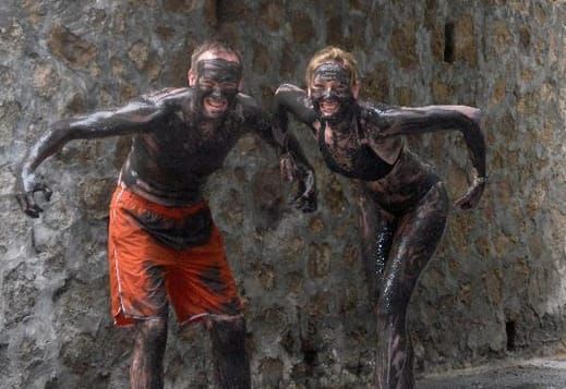 A man and a woman are covered in mud and standing next to each other.