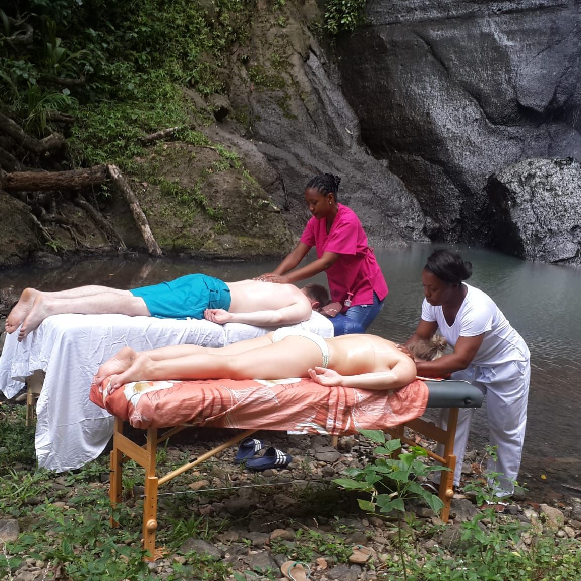 Two people are getting a massage in front of a waterfall