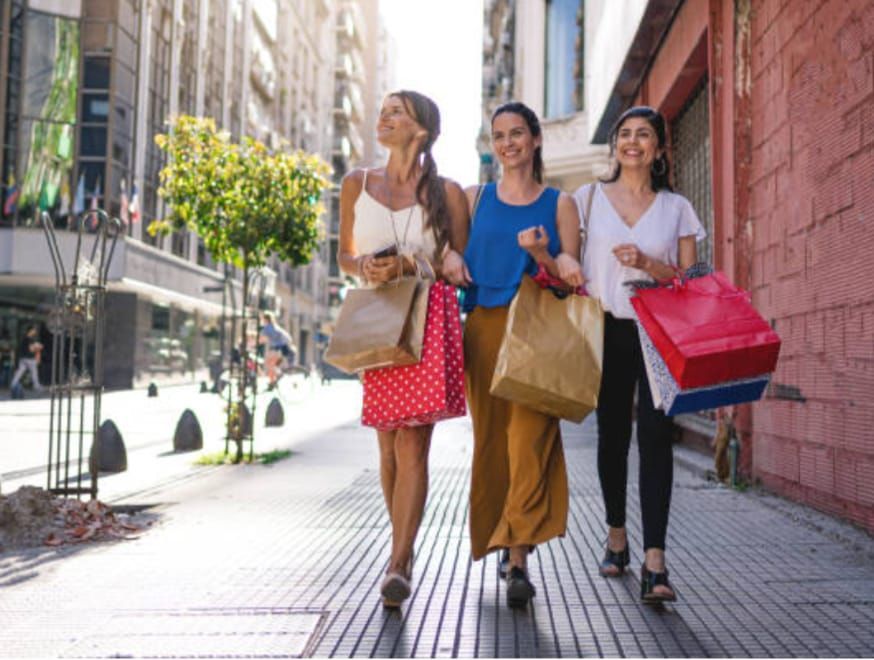 Three women are walking down a sidewalk with shopping bags