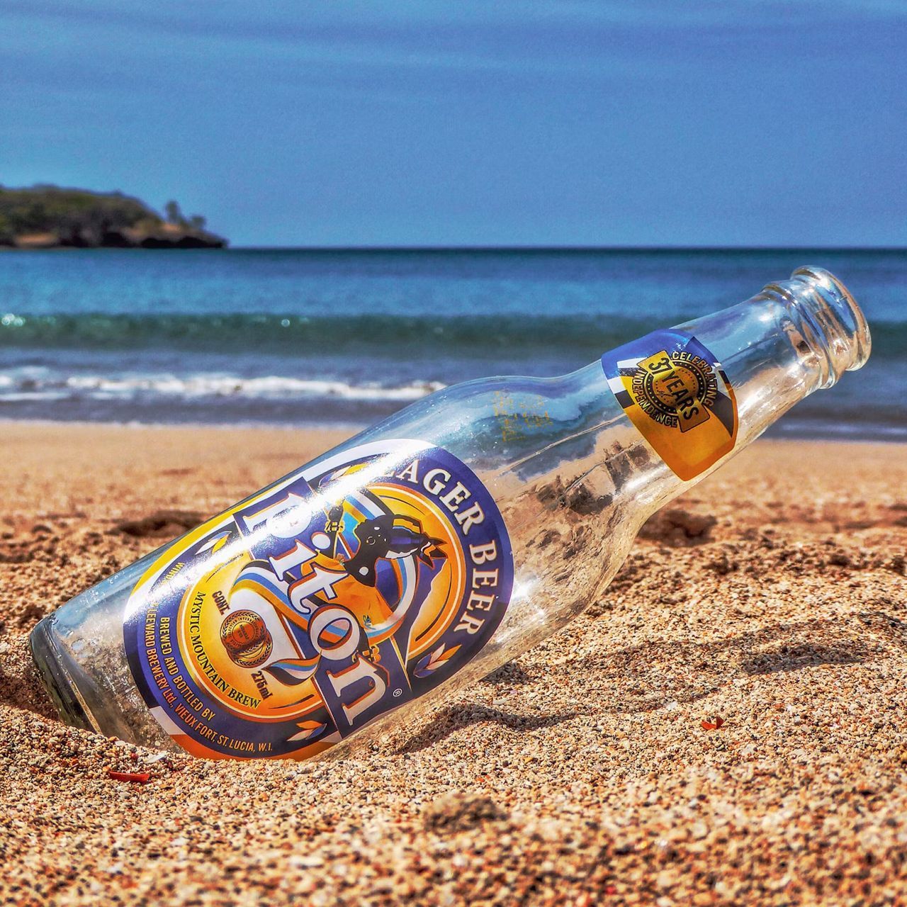 An empty bottle of tiger beer is laying on the beach.