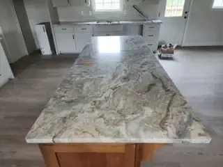 A kitchen with a large granite counter top and wooden cabinets.