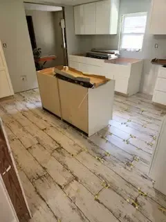 A kitchen with a wooden floor and white cabinets.