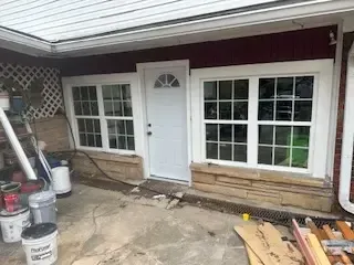 A house with a white door and windows is being remodeled.