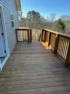 A large wooden deck with a railing on the side of a house.