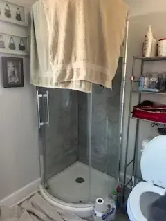 A bathroom with a toilet and a shower with a towel hanging over it.