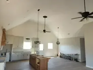A kitchen with a vaulted ceiling and a ceiling fan.