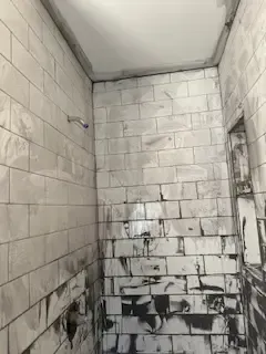A bathroom with a brick wall and a shower head.