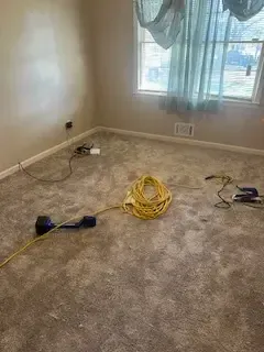 A room with a carpeted floor , a window and a bunch of tools on the floor.