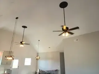 Three ceiling fans are hanging from the ceiling of a living room.