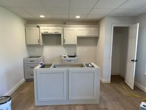 A kitchen with white cabinets and hardwood floors is being remodeled.
