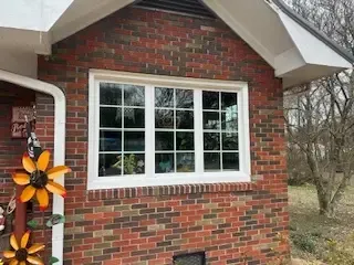 A brick house with a white window on the side of it.