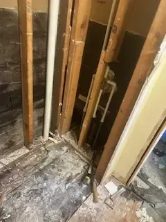 A bathroom under construction with a lot of pipes coming out of the wall.