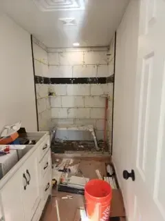 A bathroom under construction with a bathtub and a bucket on the floor.
