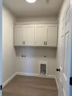 A laundry room with white cabinets and a dog door.