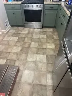 A kitchen with a stove , refrigerator , sink and cabinets.