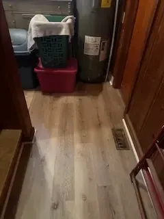 A laundry room with hardwood floors and a water heater.