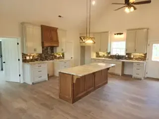 A kitchen with a large island in the middle and a ceiling fan.
