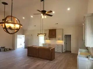 A living room with a ceiling fan and chandeliers hanging from the ceiling.