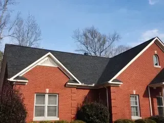 A red brick house with a black roof and white trim
