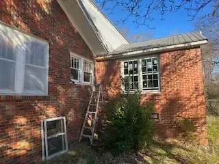 A ladder is sitting on the side of a brick house.