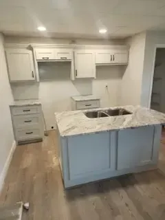 A kitchen with white cabinets , granite counter tops , and a sink.