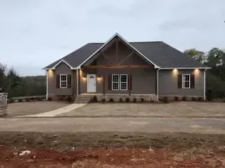 A large house with a lot of windows is sitting on top of a dirt field.