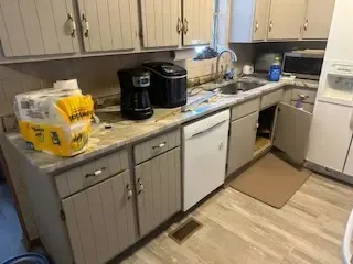 A kitchen with a sink , dishwasher , coffee maker , and paper towels on the counter.