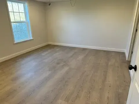 An empty room with hardwood floors and a window.