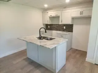 A kitchen with white cabinets , granite counter tops , and a sink.