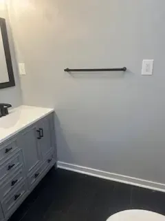 A bathroom with a sink , toilet , mirror and towel rack.