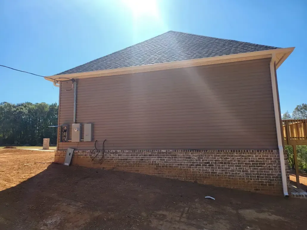A house with a metal roof is sitting on top of a dirt field.