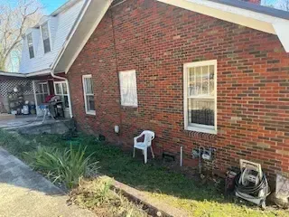A brick house with a white chair in front of it.