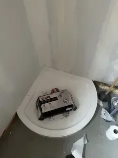 A box of wipes is sitting on top of a toilet in a bathroom.