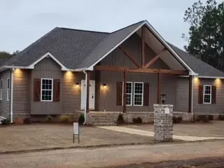 A large house with a lot of windows and a stone pillar in front of it.