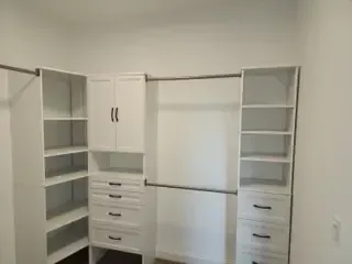 A walk in closet with lots of shelves and drawers.