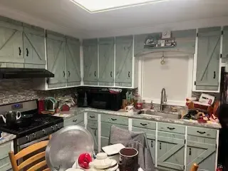 A kitchen with a stove , sink , cabinets and a table.