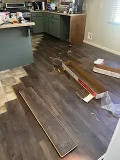 A kitchen with a wooden floor being installed.