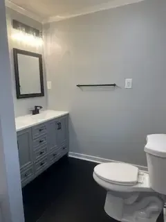 A bathroom with a toilet , sink and mirror.