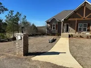 A house with a walkway leading to it and a brick pillar in front of it.