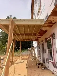 A wooden deck is being built on the side of a house.
